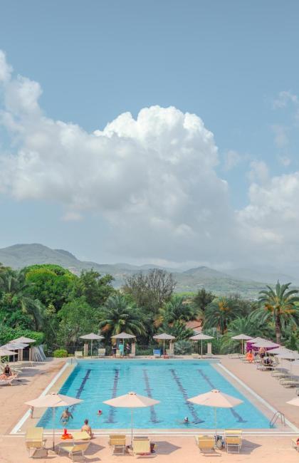 Piscina all'aperto circondata da palme e montagne.