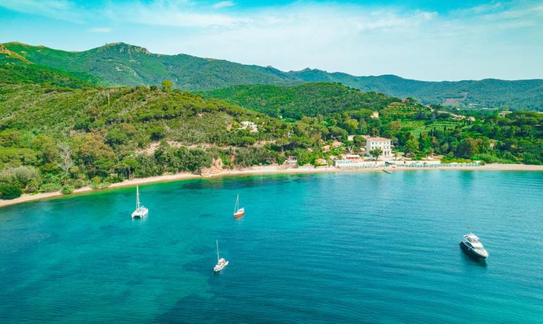 Peaceful beach with boats and green hills, perfect for a relaxing vacation.