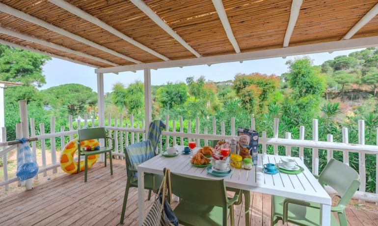 Veranda with outdoor breakfast and green view.